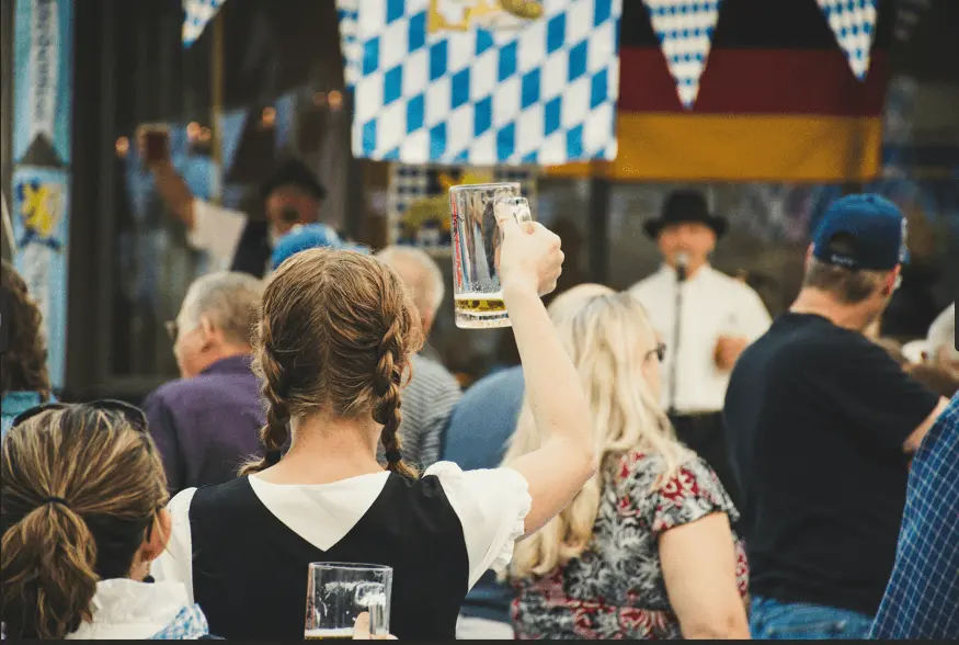 people from behind raising their beer glasses at Oktoberfest in Munich
