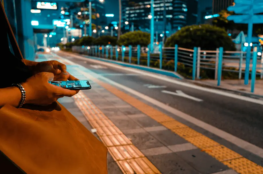person holding phone while waiting for the bus in Japan
