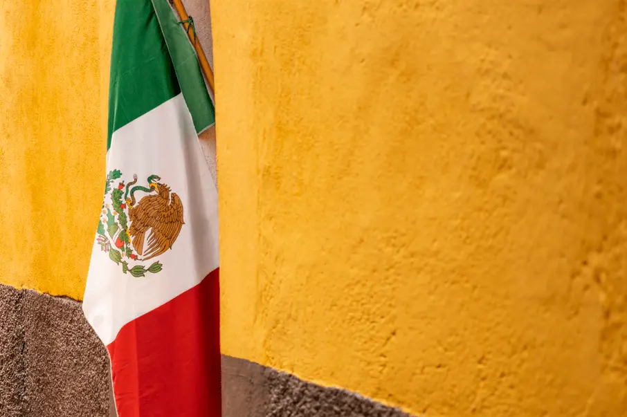 mexican flag in front of a yellow and brown wall