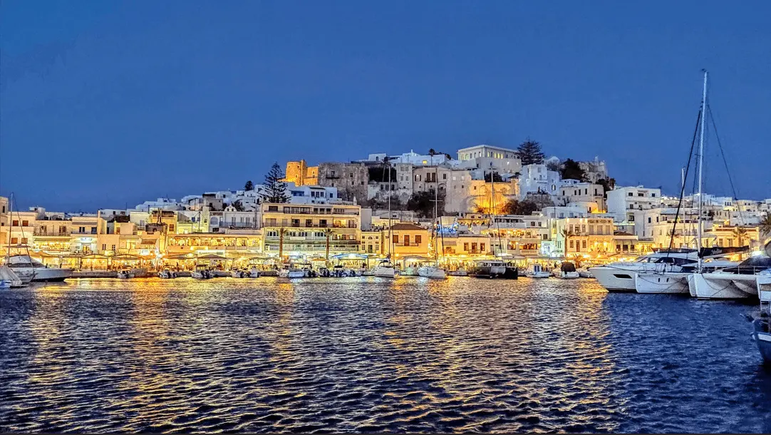 nighttime view of the Greek Islands with lit up houses and boats
