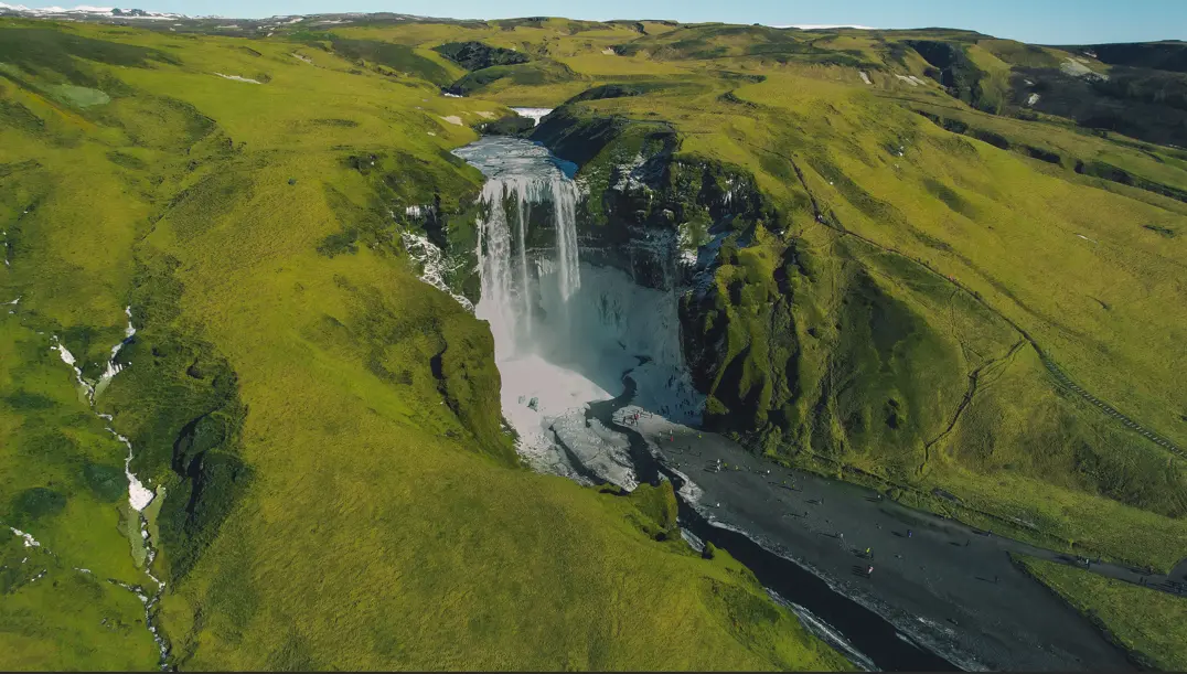 Aerial view of a waterfall in the middle of Iceland with lush greenery around it