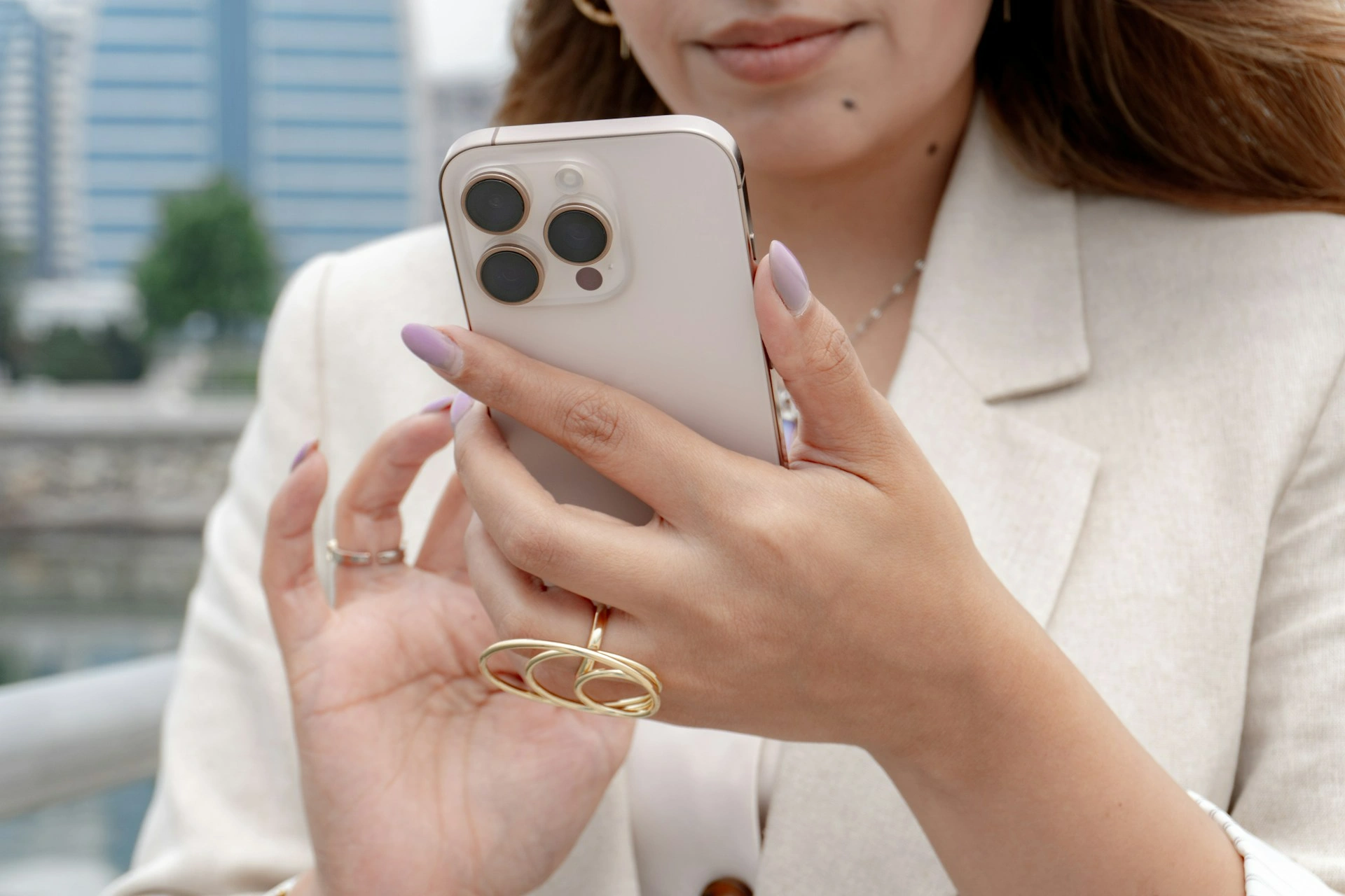 women in beige blazer holding her phone while typing