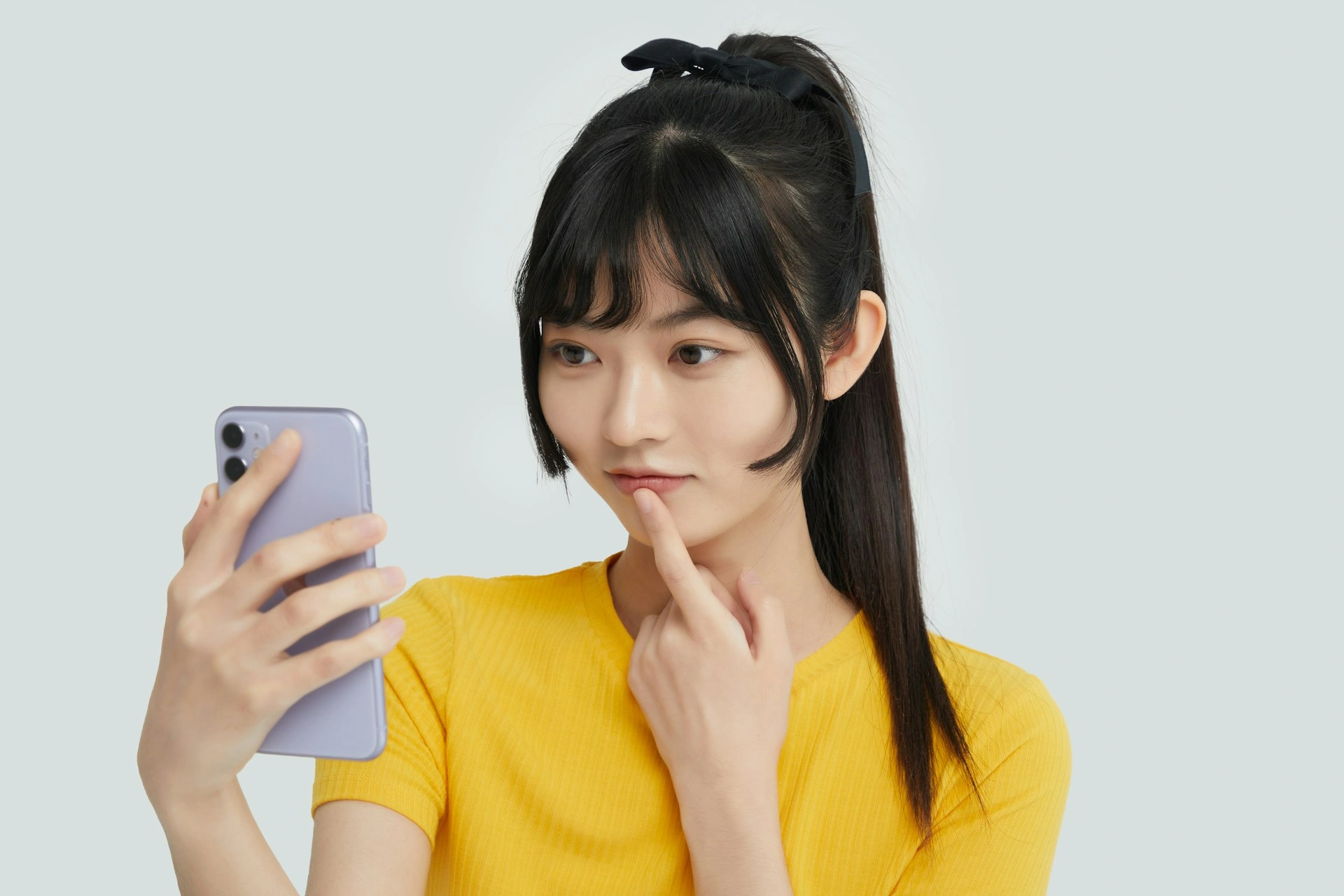 woman in yellow shirt holding her phone in her right hand