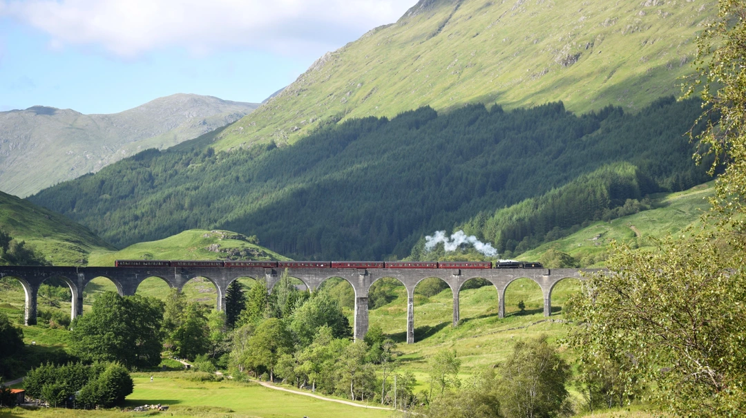 Steam train crossing the iconic Glenfinnan Viaduct in Scotland's Highlands