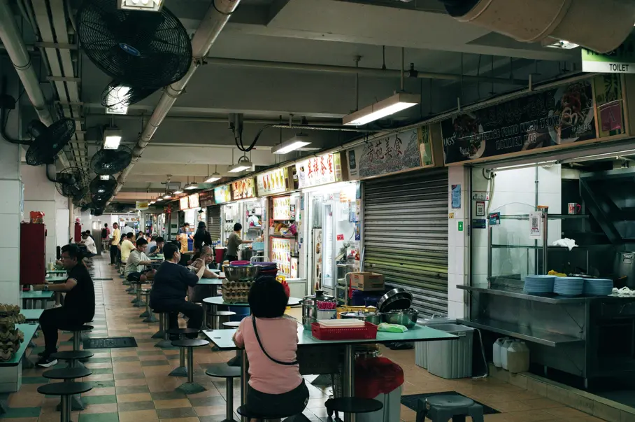 People sitting at tables eating inside a hawker center in Singapore