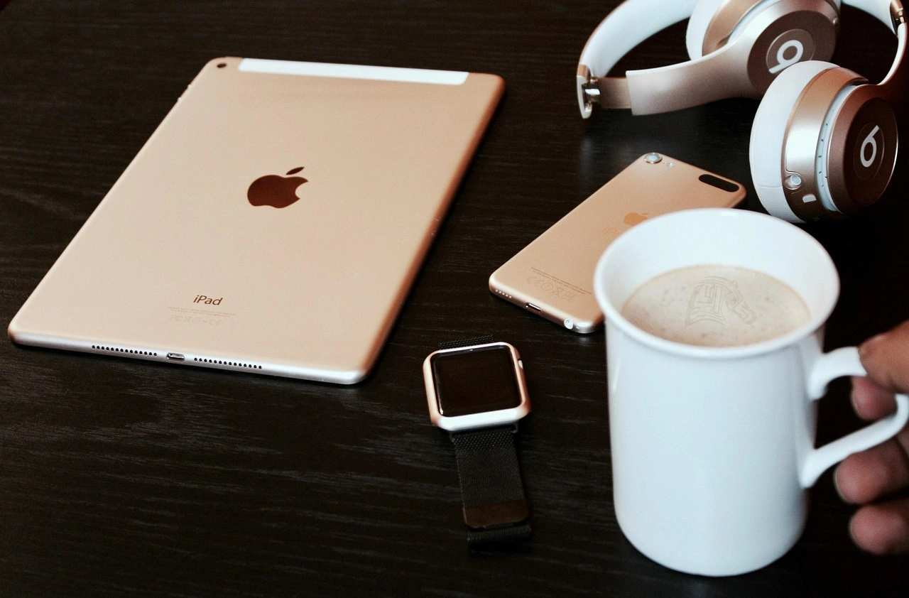 wooden table with esim connected tablet, phone, watch and headphones